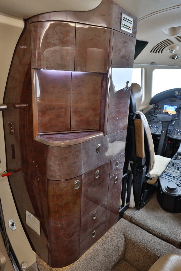 View of the interior of a Citation XLS+ aircraft, showing the cockpit and a cabinet.
