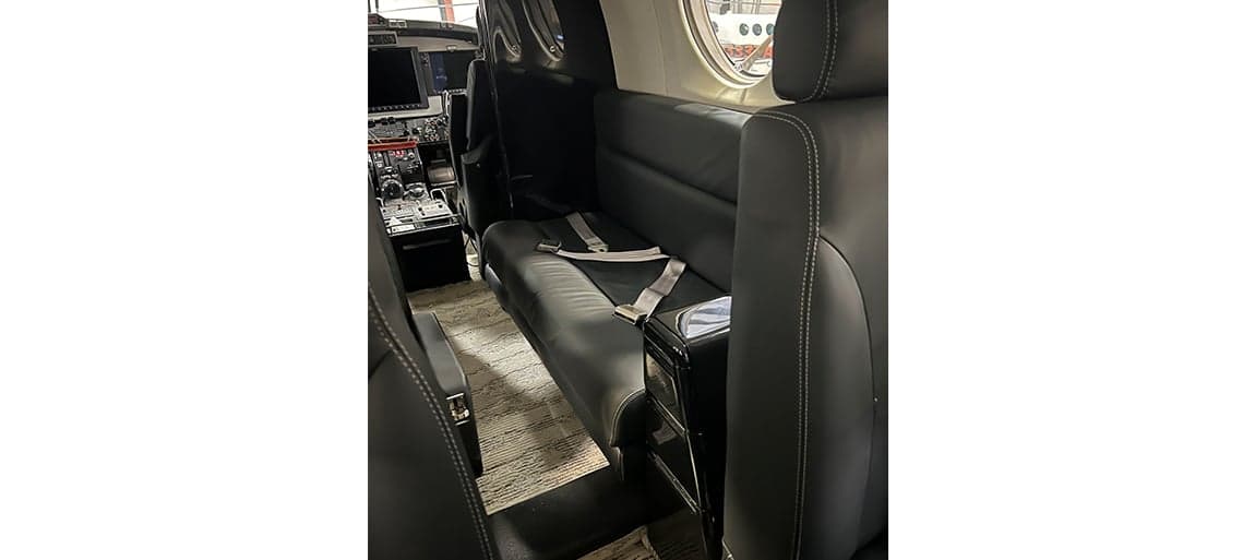 View of the aircraft interior showing the black leather seats and carpeted floor.