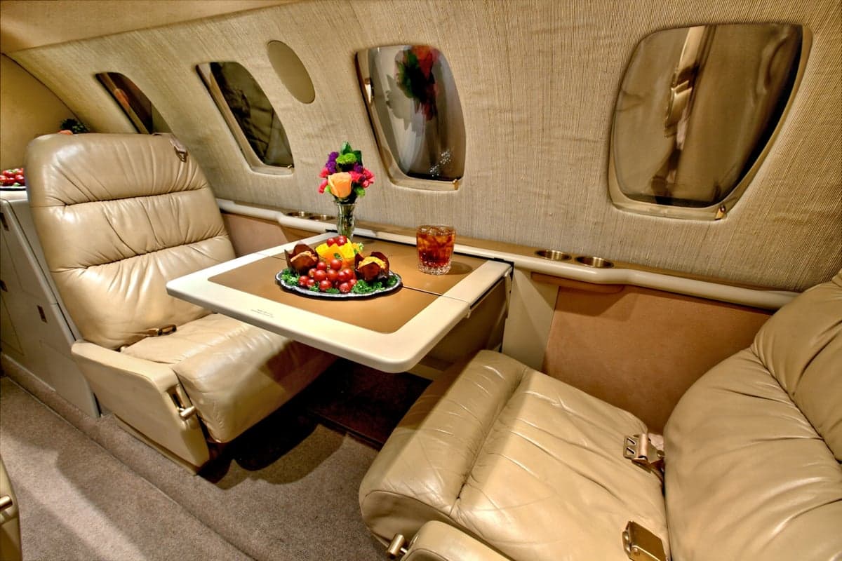 A close-up of the CitationJet's interior shows a table with refreshments.