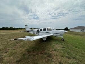 Beechcraft Bonanza N333SM parked on a grassy field.