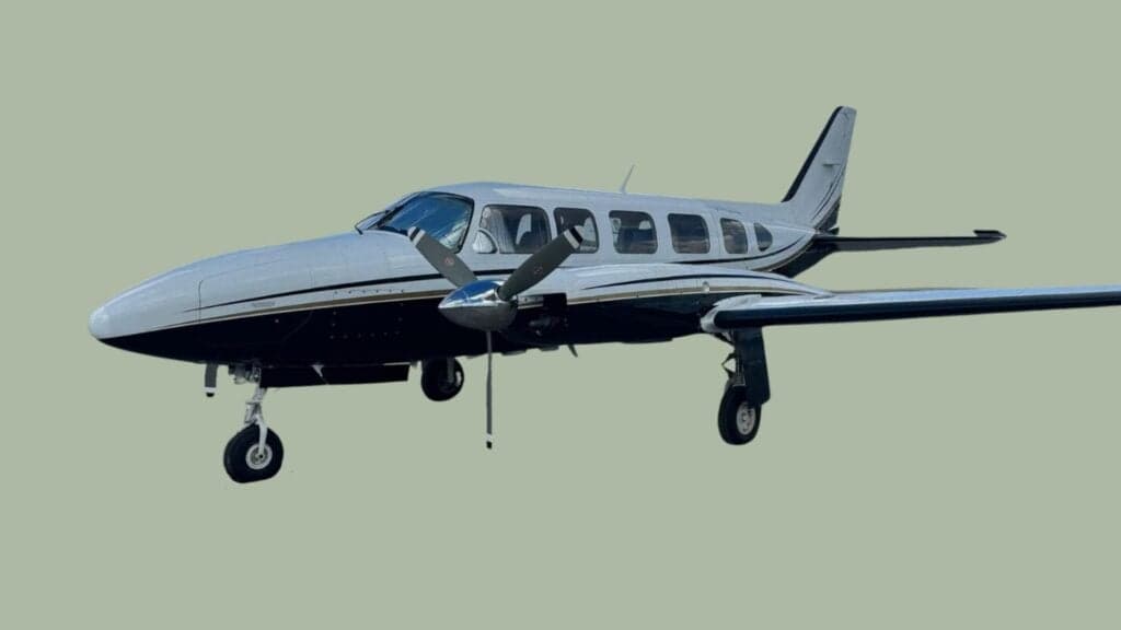 A side view of a twin-engine aircraft with a silver and black paint scheme.
