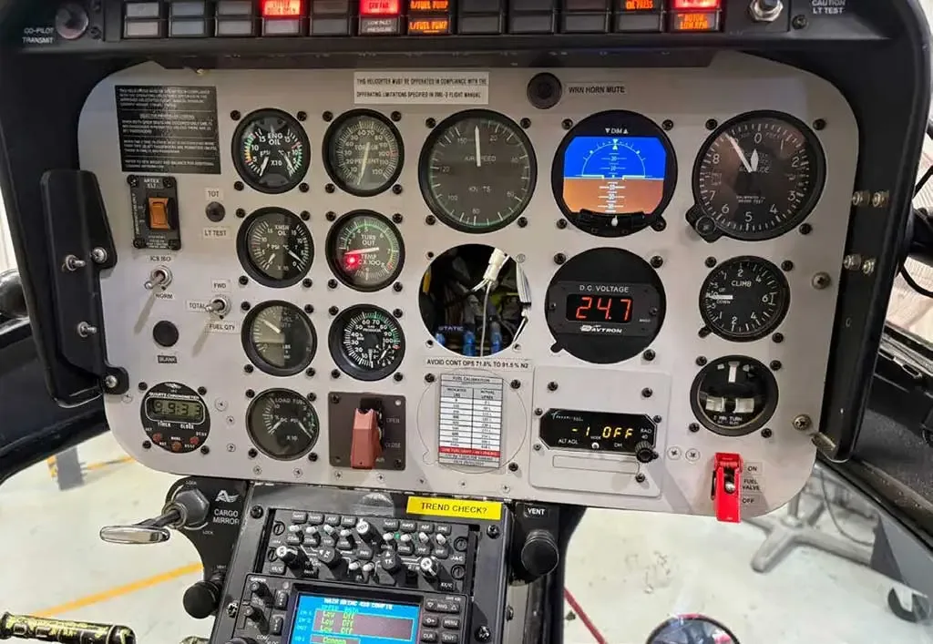A detailed view of a helicopter's instrument panel, featuring numerous analog gauges, digital displays, and control switches.