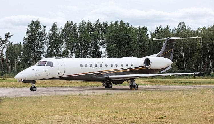 Embraer Legacy 650 parked on a grassy airfield.