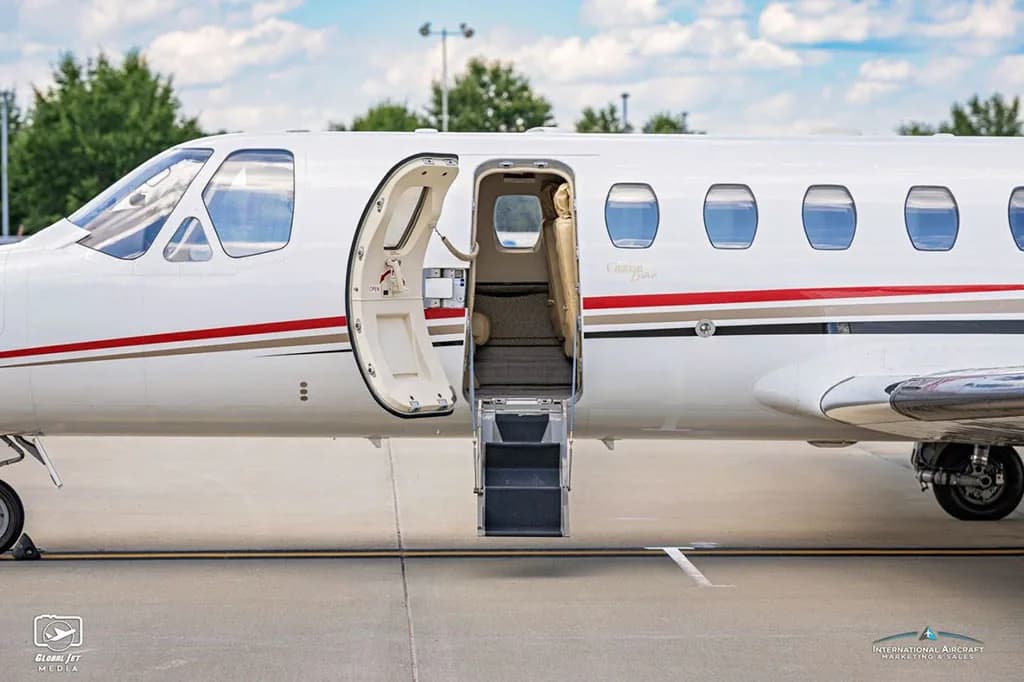 A side view close-up of the open passenger door and airstairs of a white Cessna Citation Bravo business jet.
