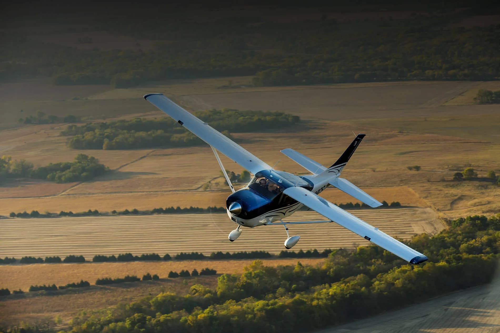 A Cessna Stationair in flight over a rural landscape.