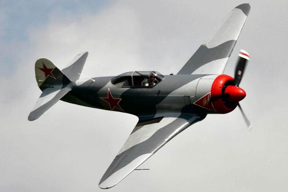 A Yakovlev Yak-3 fighter aircraft in flight with a gray camouflage paint scheme and red star markings.