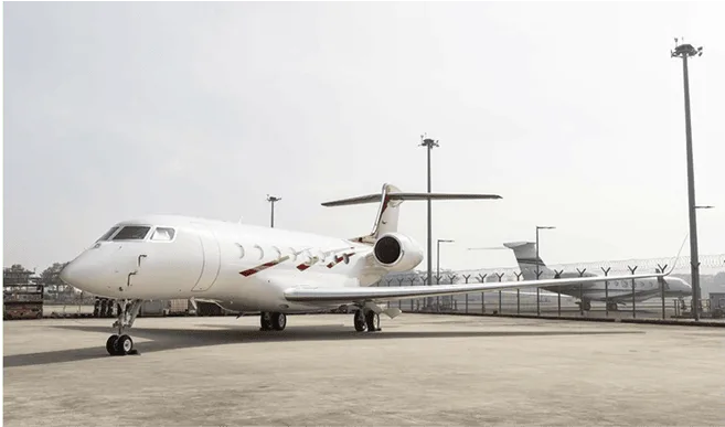 A white Gulfstream business jet with red accents parked on an airport tarmac.