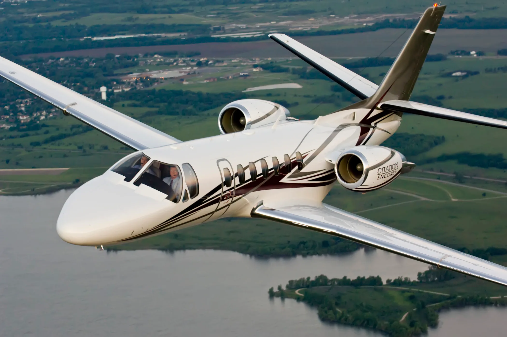 Citation Encore flying over a lake.