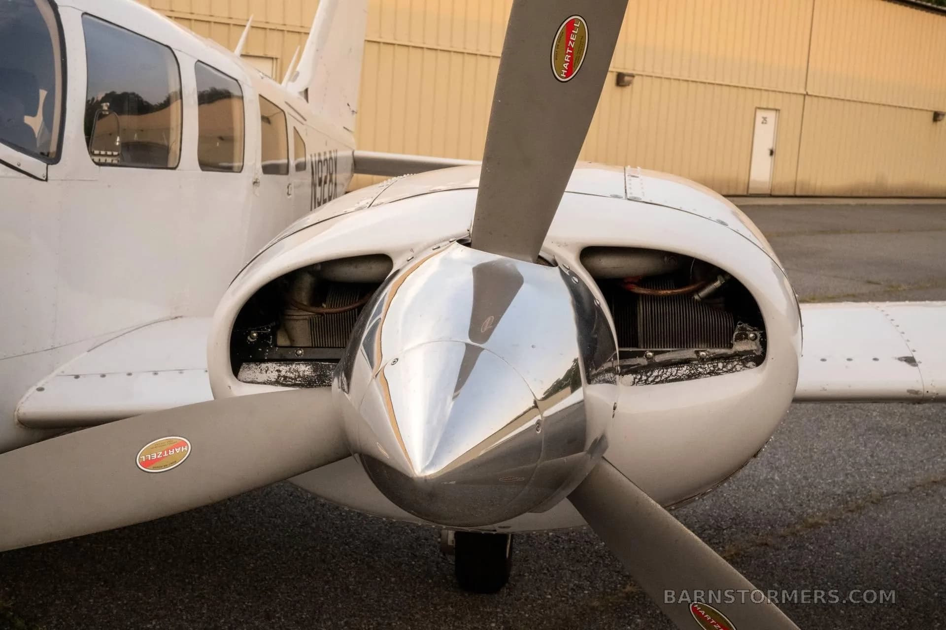 A close-up view of the right engine and propeller of a white twin-engine aircraft, showing the Hartzell propeller.