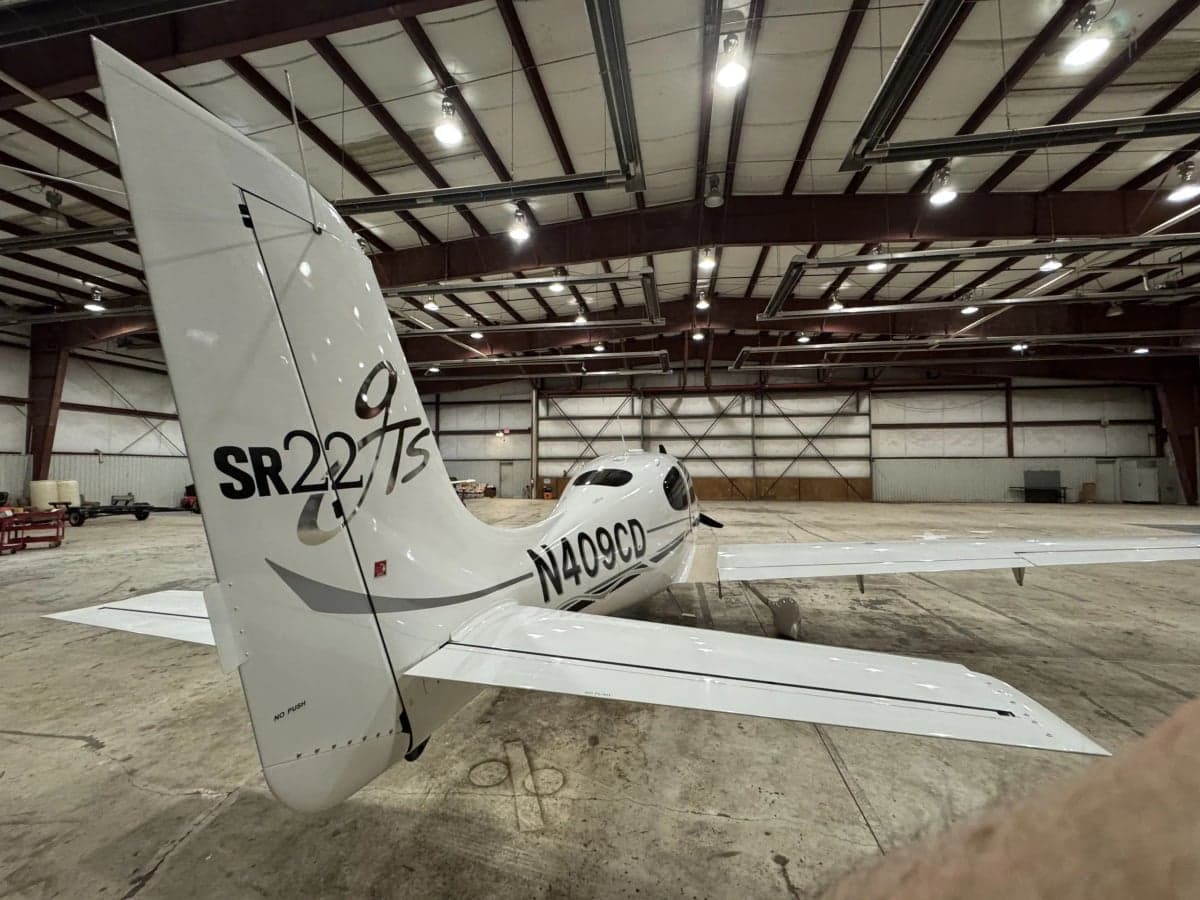 Rear view of a Cirrus SR22T in a hangar, showing the tail and registration number N409CD.