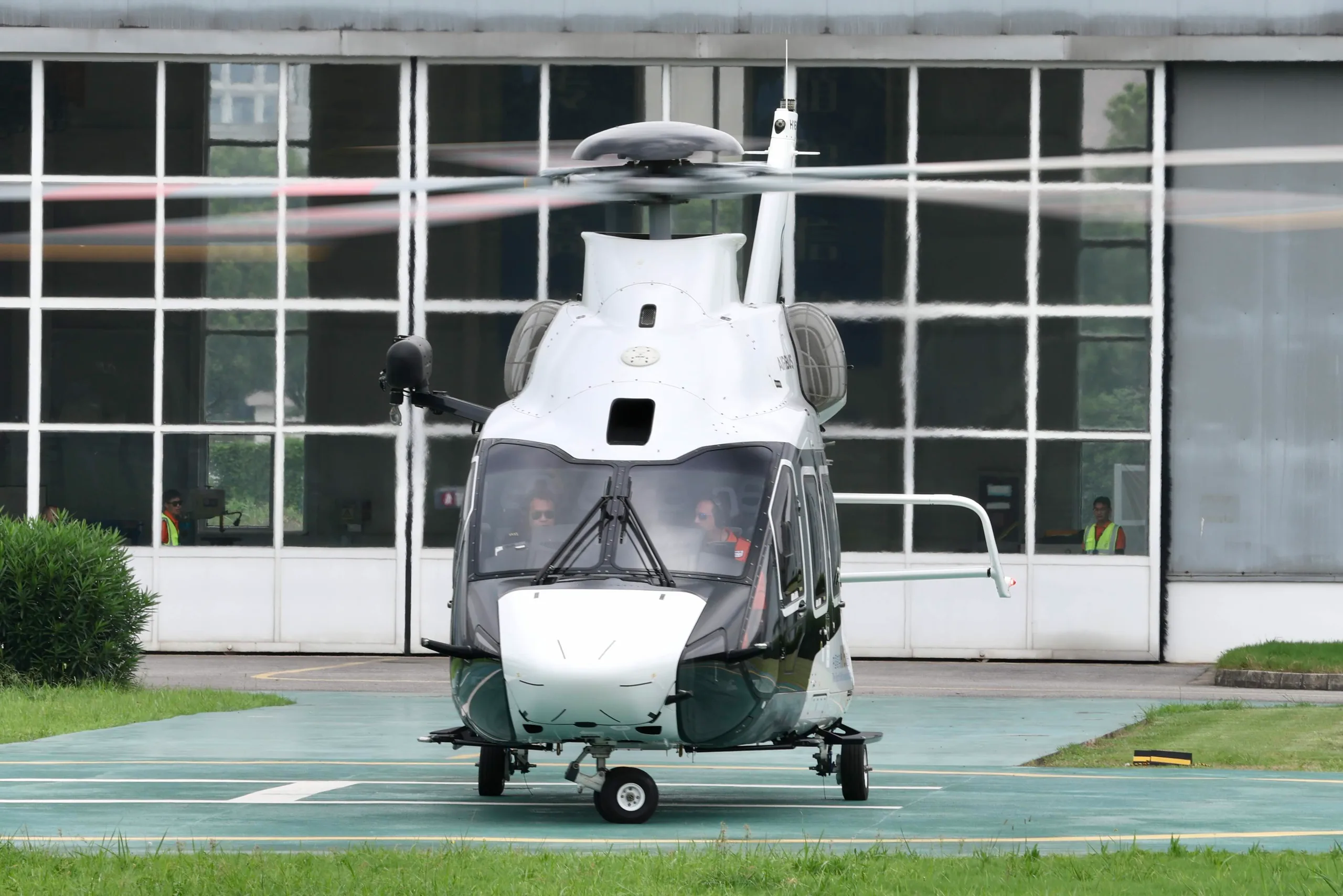 Front view of a white and black Airbus H160 helicopter on a helipad.