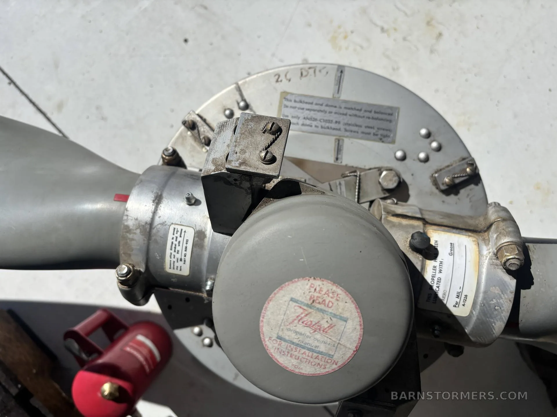 A close-up view of an aircraft propeller hub, showing various labels, bolts, and mechanical connections.