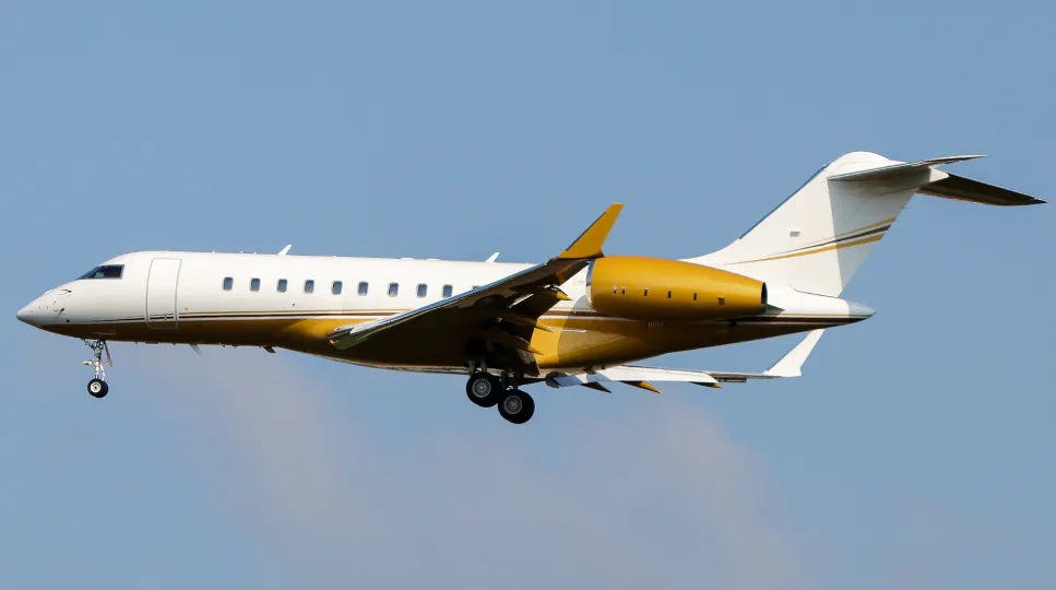 A Bombardier Global aircraft in flight with gold accents.