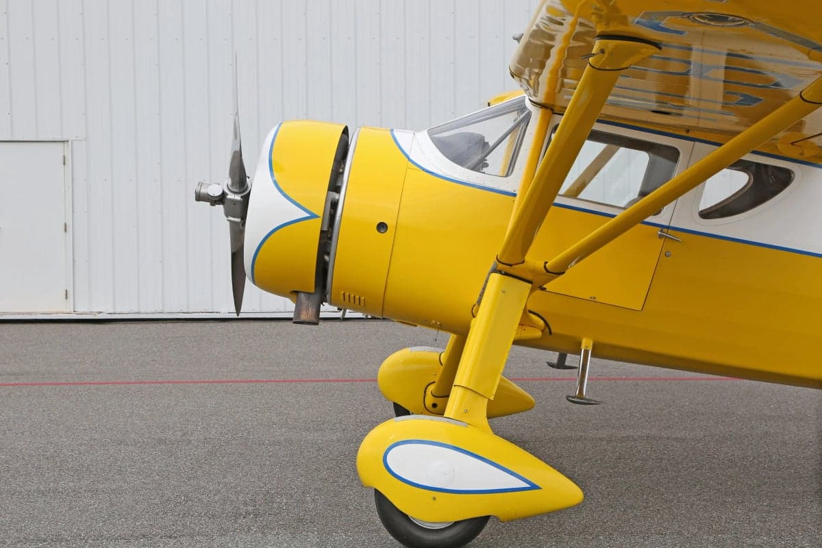 Close up of the front of a yellow and white Stinson Reliant parked on the tarmac.