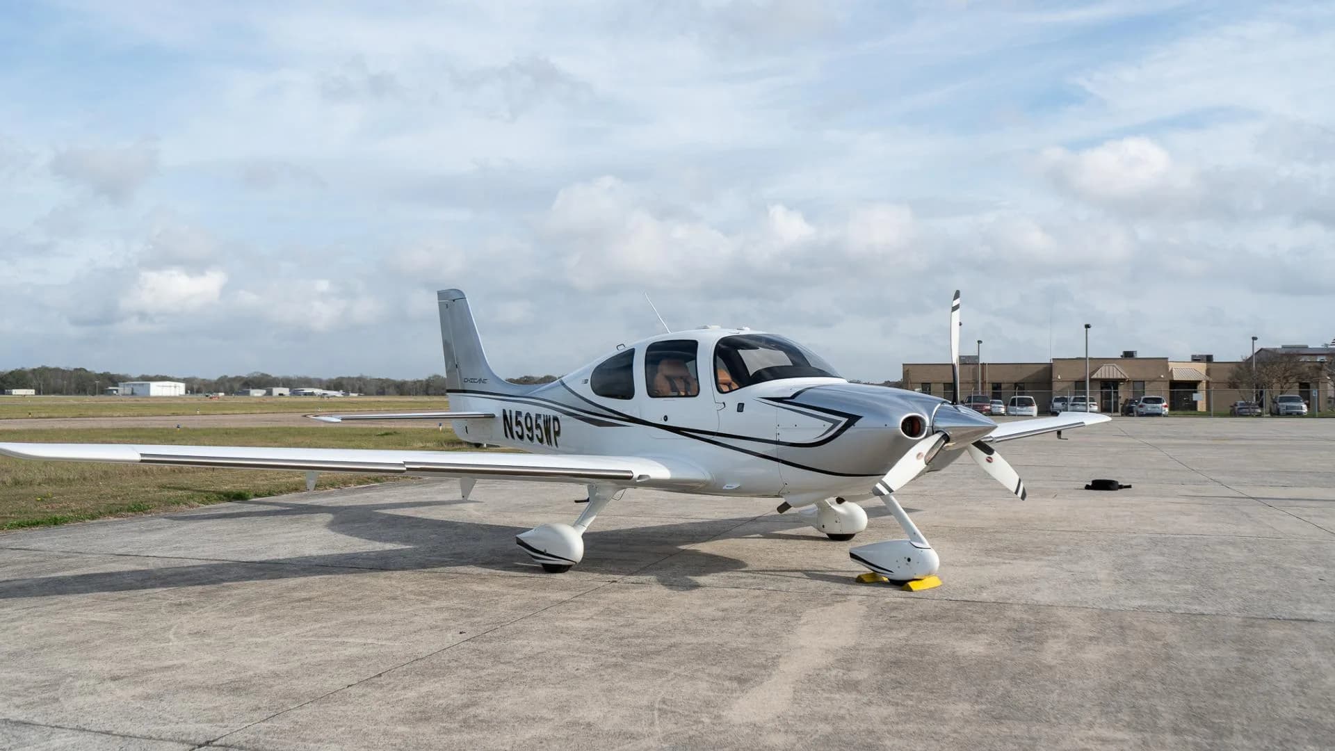 A white Cirrus SR22 aircraft with silver and black accents, registration N595WP, parked on an airfield.
