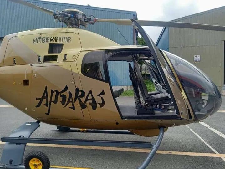 Side view of a gold helicopter with the door open, showing the interior.