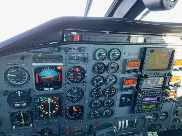 A close-up view of the pilot's side instrument panel, showing various gauges, screens, and controls, with N411BG visible on a placard.
