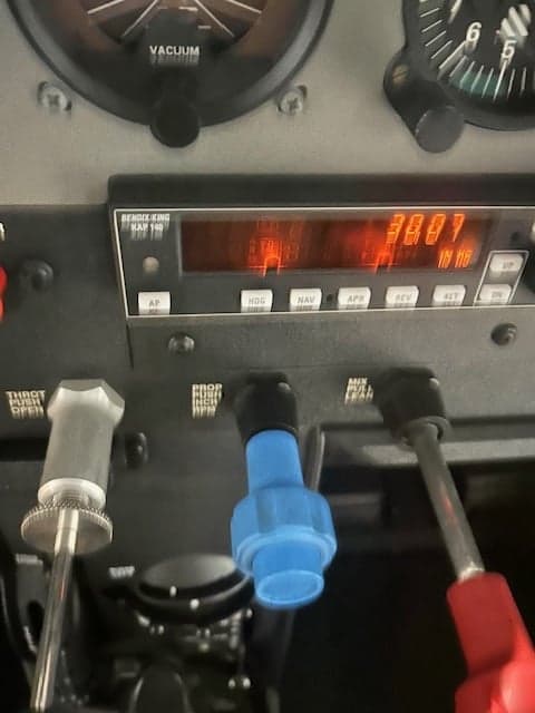A close-up of an aircraft's instrument panel, showing a Bendix King autopilot control unit and engine controls.