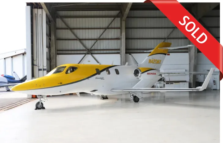 HondaJet in a hangar with a yellow and white paint scheme, marked with a SOLD banner.