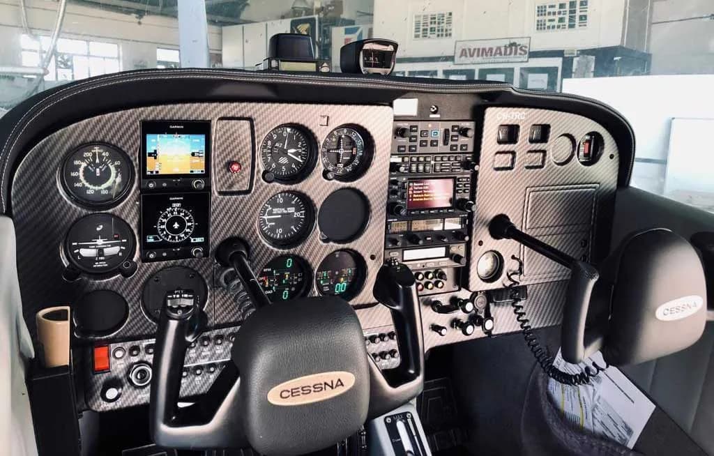 The cockpit instrument panel of a Cessna aircraft, featuring a carbon fiber look, modern avionics, and traditional gauges.