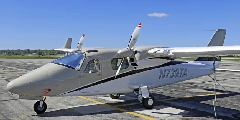A beige and white twin-engine aircraft, N739TA, parked on an asphalt ramp.