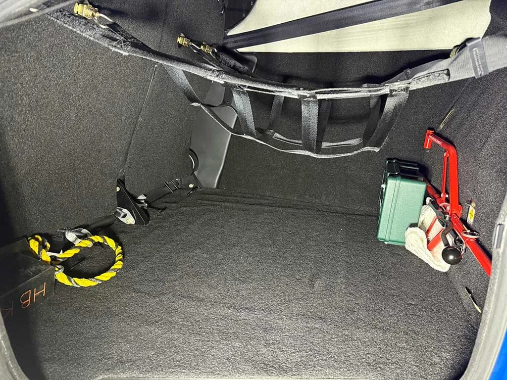 The carpeted baggage compartment of a Cirrus SR22T aircraft, showing a cargo net and some equipment.