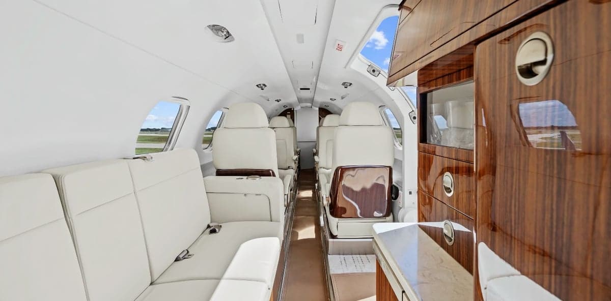 The interior of a Phenom 300 aircraft with white leather seats.