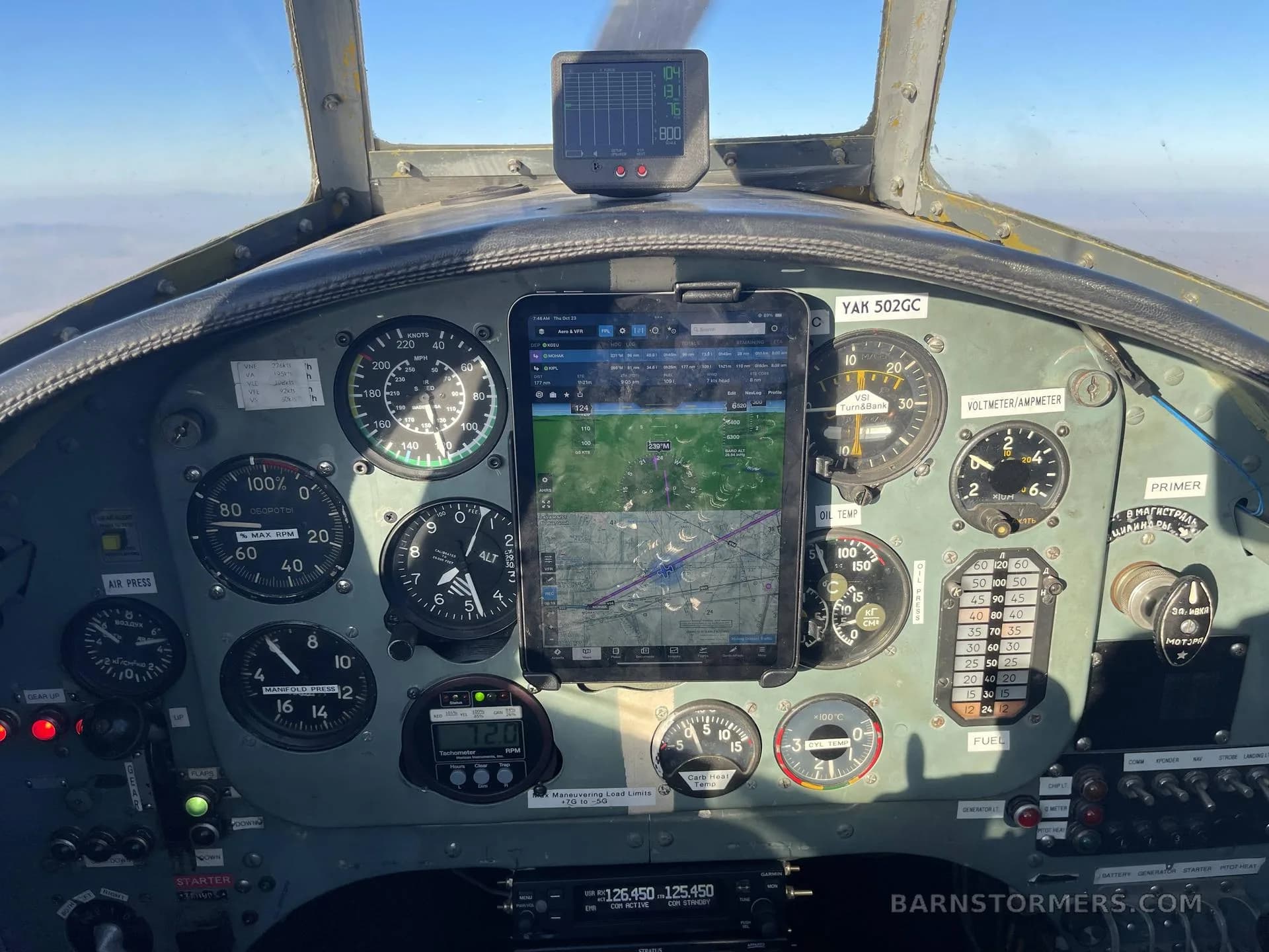 The cockpit instrument panel of a Yak-502GC aircraft, featuring analog gauges and two modern tablet displays.
