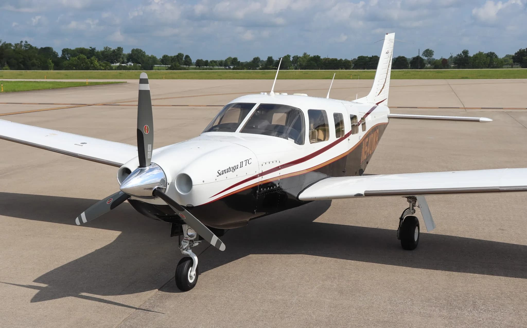 A front three-quarter view of the Piper Saratoga II TC aircraft, N540WB, with white, black, and red paint scheme, parked on an airfield.