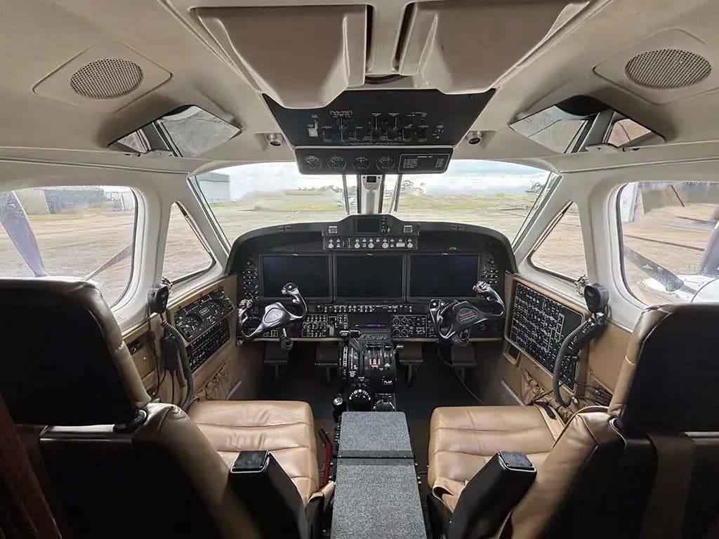A detailed view of the aircraft cockpit, featuring the modern instrument panel with multiple screens and pilot controls.