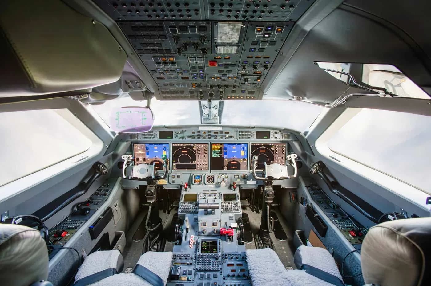 The modern cockpit of a business jet with multiple digital displays and control panels.