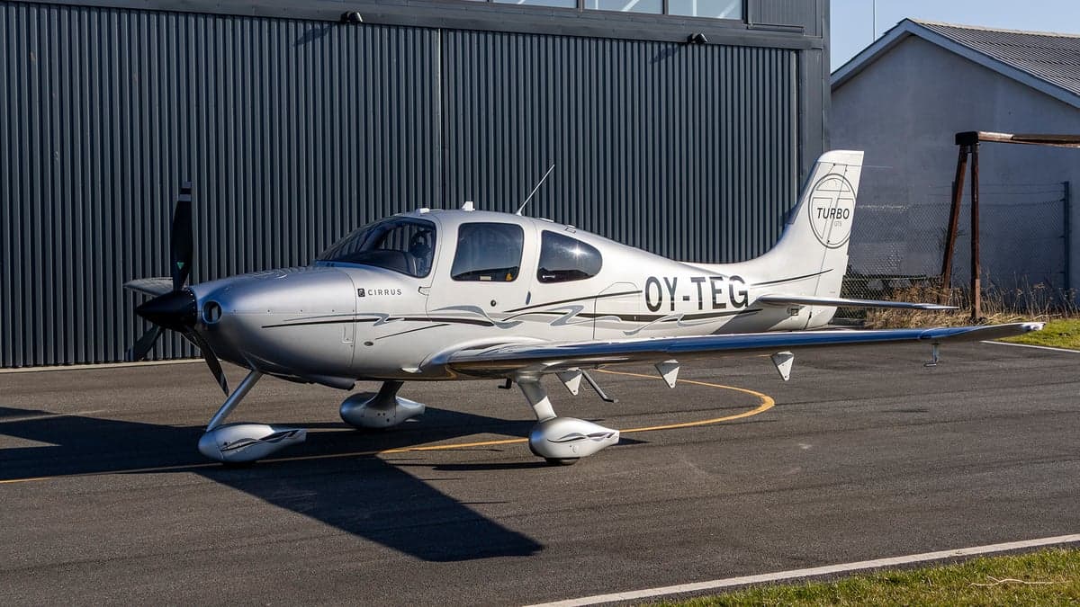 Side view of the silver Cirrus OY-TEG on the tarmac.