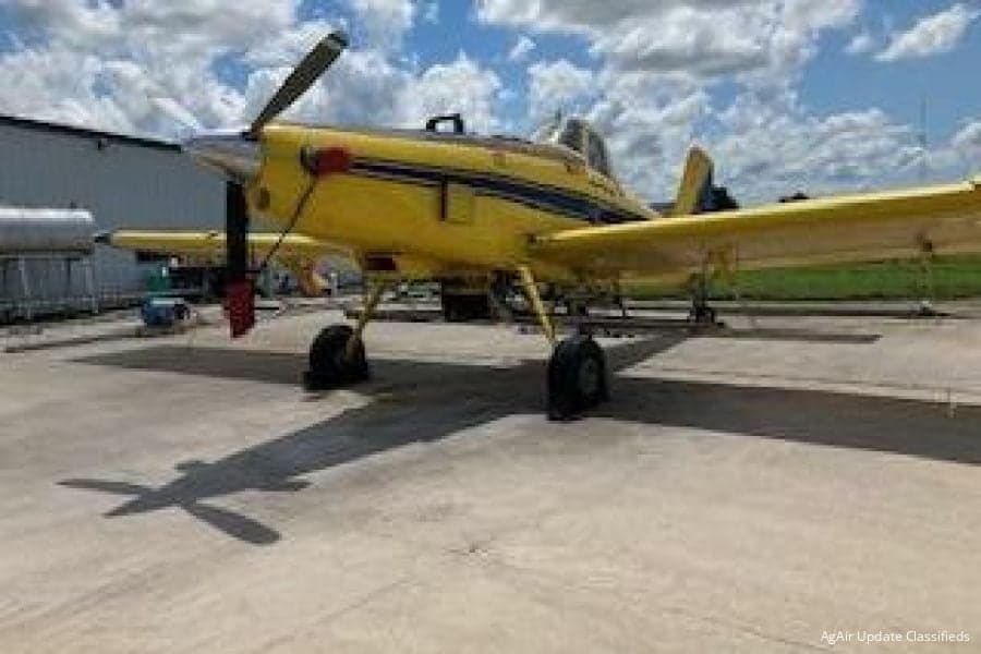 Yellow and blue agricultural aircraft parked on a concrete surface.