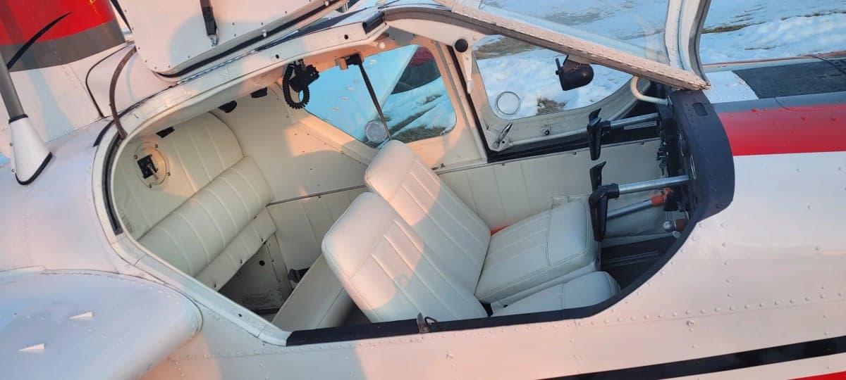The interior of the aircraft features white seats and an open door.