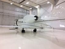 Rear view of a Learjet parked inside a hangar with a shiny floor.