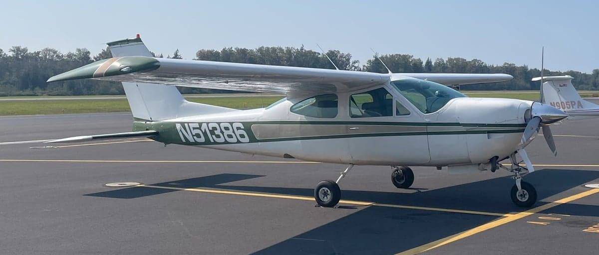 A white and green Cessna Cardinal RG II, registration N51386, is parked on the tarmac at an airport.