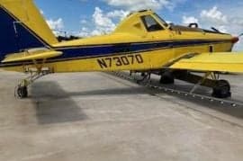 Close up of the side of a yellow and blue agricultural aircraft.