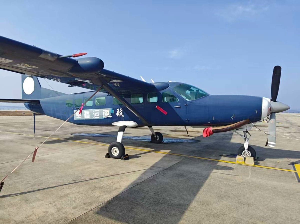 A blue aircraft is parked on the tarmac on a sunny day.