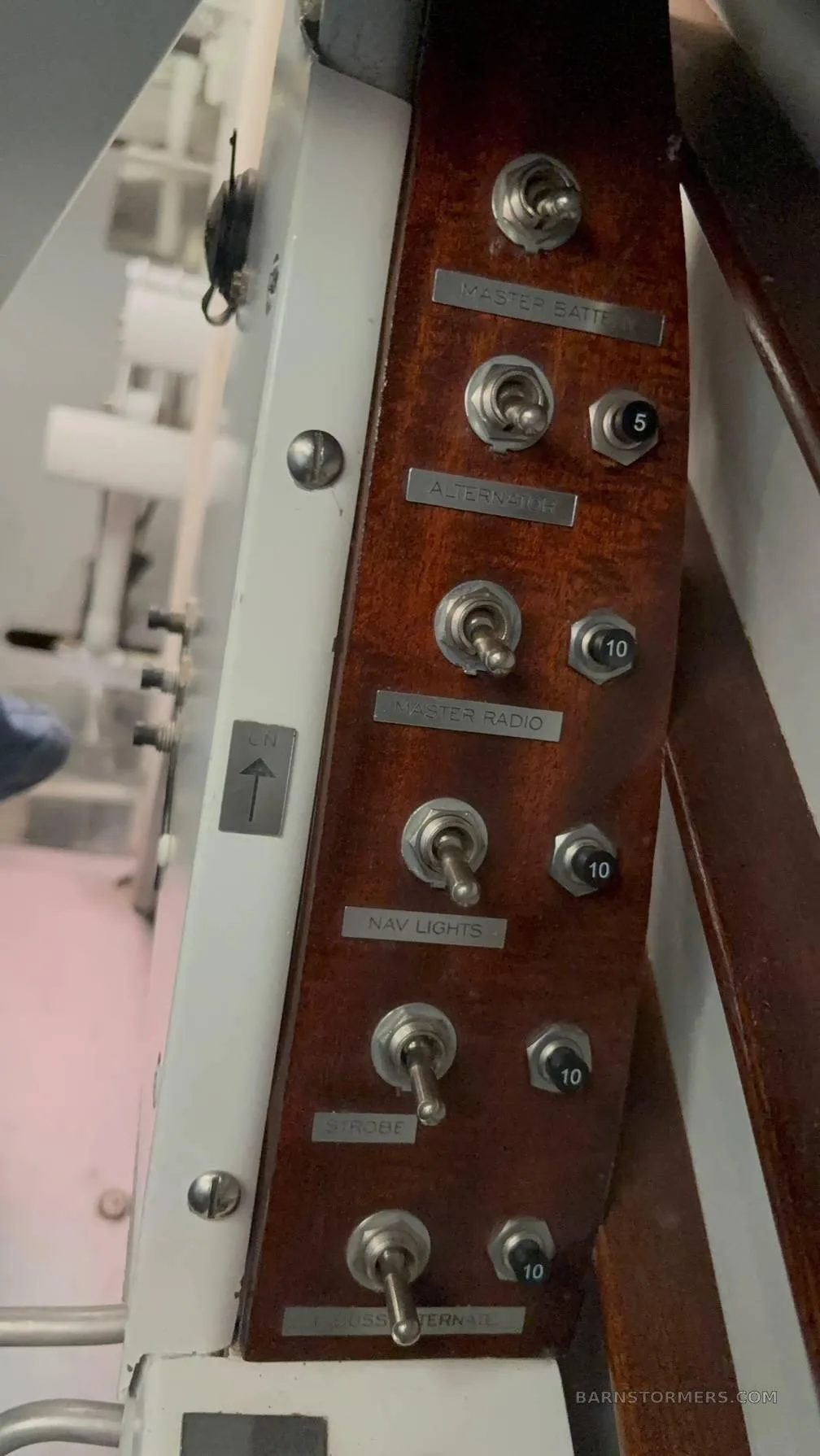 A close-up view of a wooden switch panel with toggle switches labeled for master battery, alternator, radio, and lights.