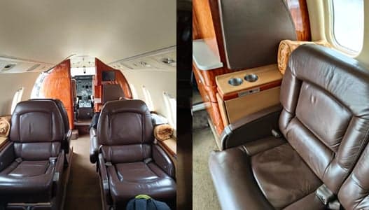 The interior of the Learjet aircraft features leather seats and wood trim with a view of the cockpit.