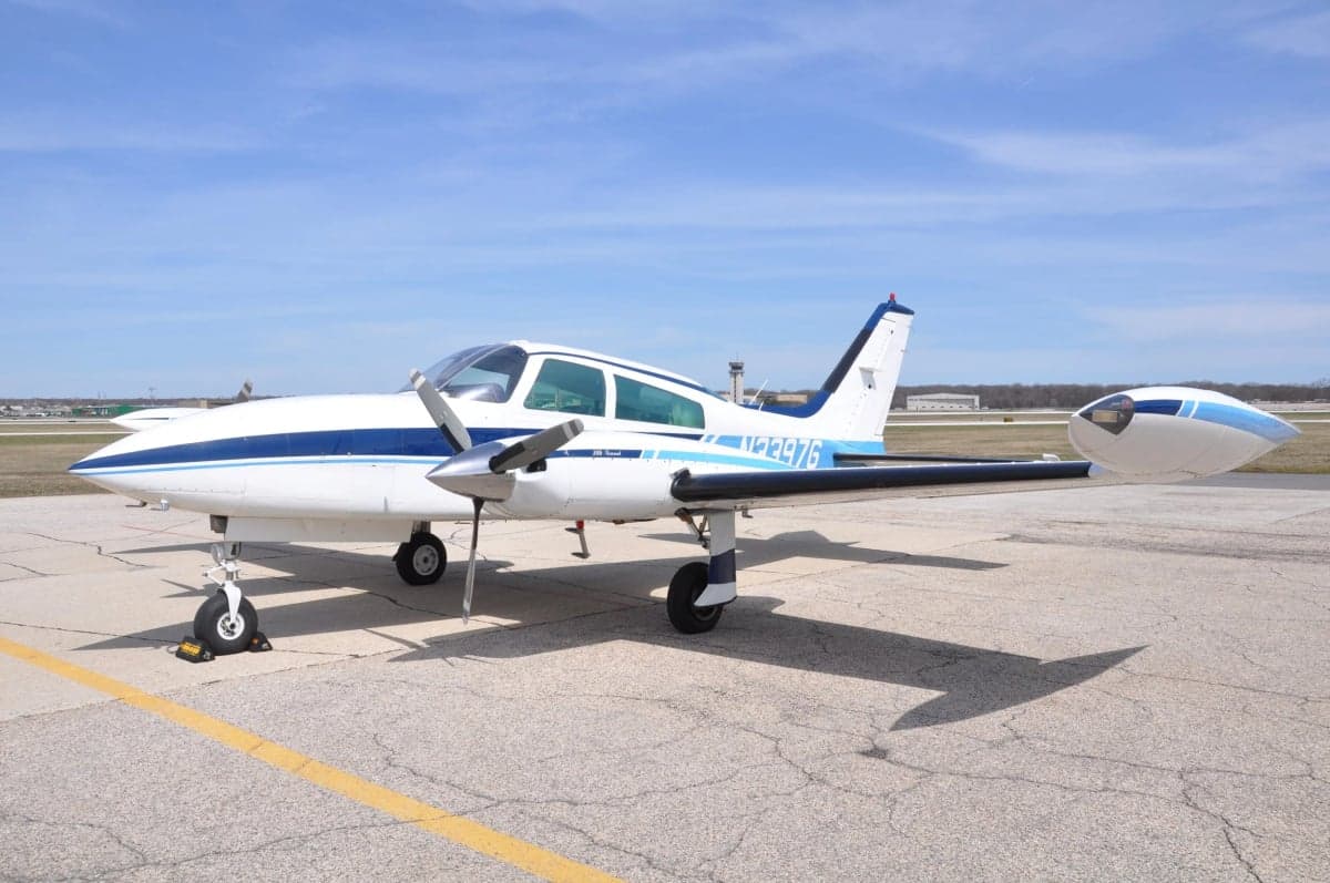 Side view of a white and blue Twin Commander aircraft on the tarmac.