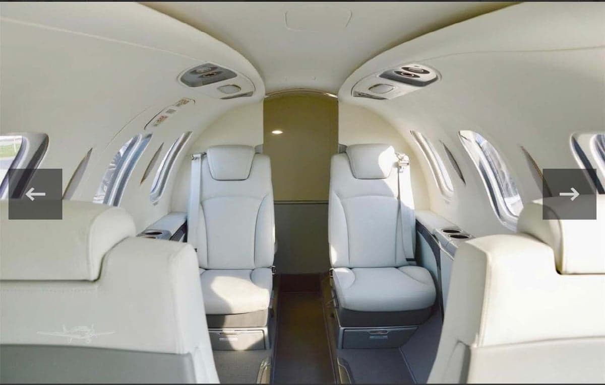 The aircraft's interior features white leather seats and a spacious cabin.