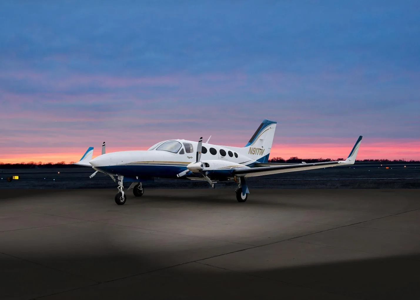 A white and blue Cessna 414 Chancellor (N91TW) parked on an airfield at sunset, viewed from the front-right.