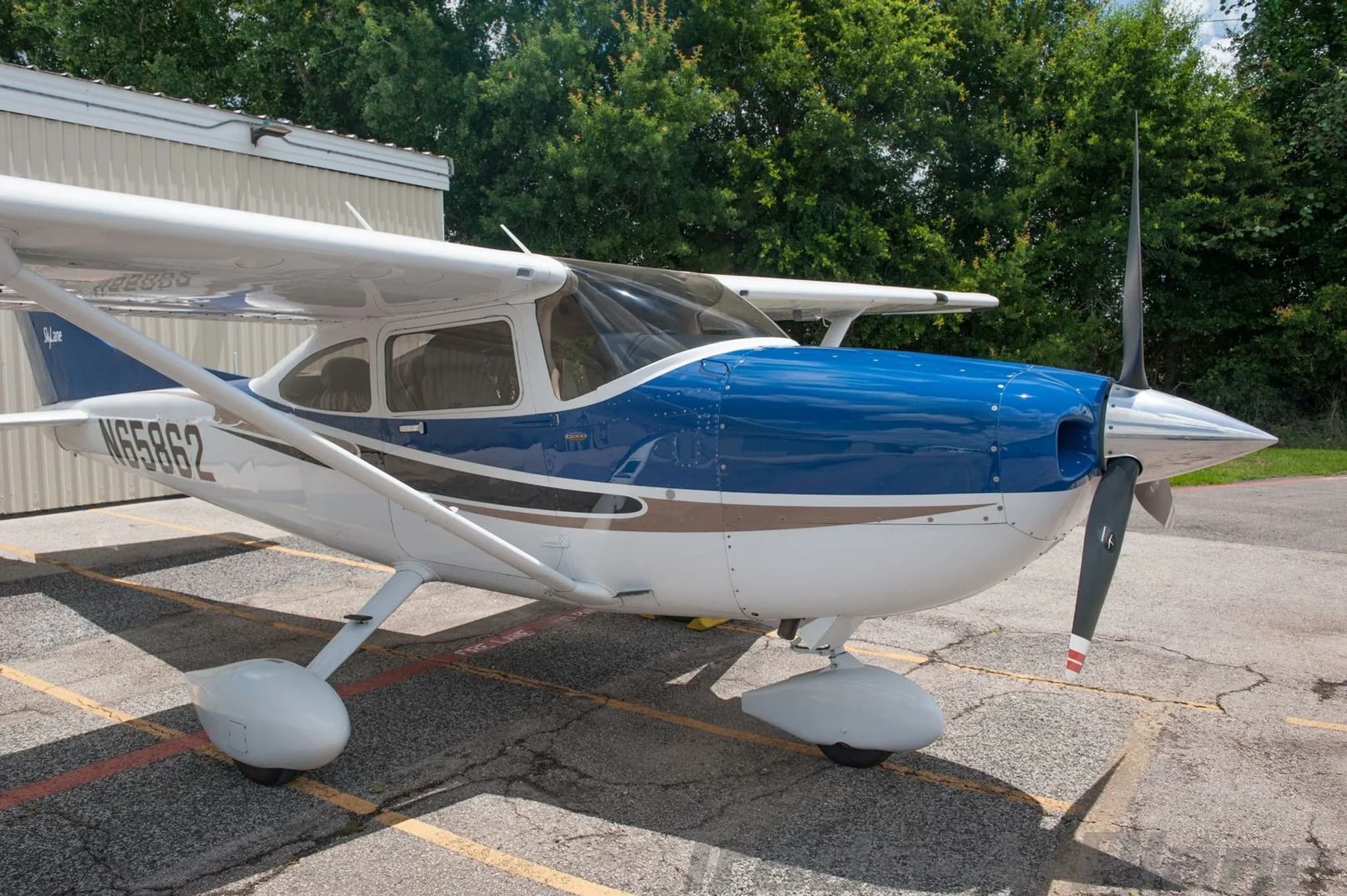 A front-right view of a white and blue Cessna Skylane N65862 parked on an asphalt ramp.