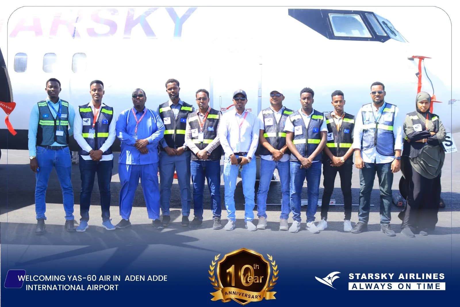 A group of airline staff stands in front of a white Starsky Airlines aircraft on the tarmac at Aden Adde International Airport.