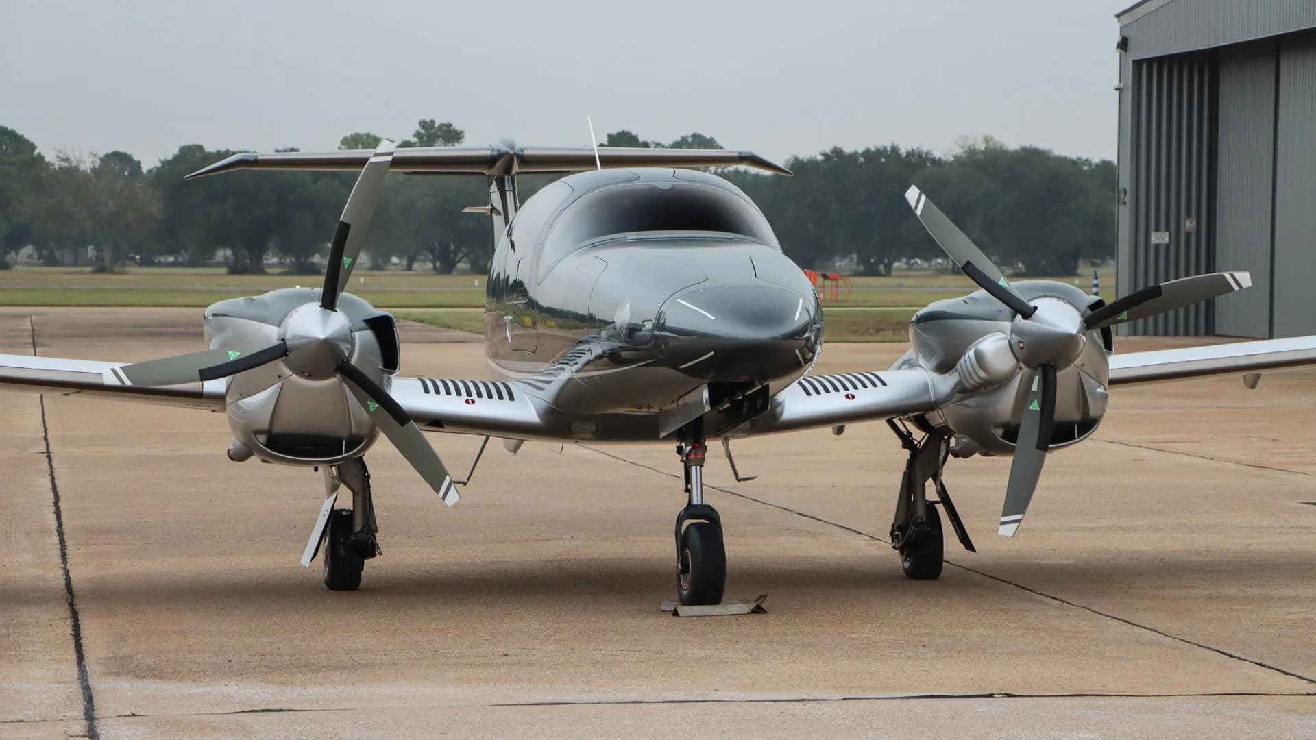 A front view of the gray and silver Diamond DA62 aircraft, N502LA, parked on an airport tarmac.
