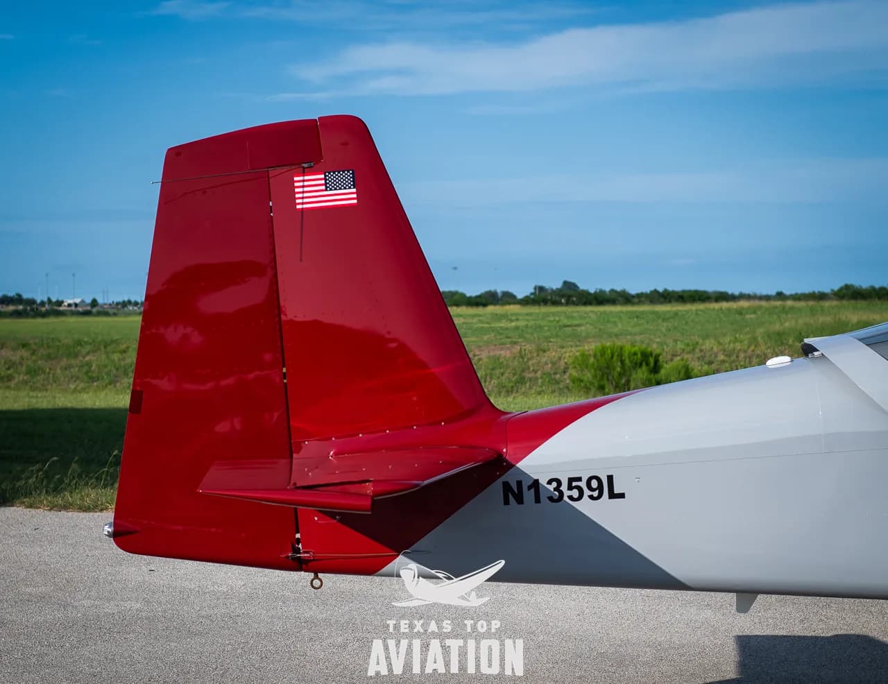 A close-up of the red tail of N1359L, featuring an American flag decal and the tail number.