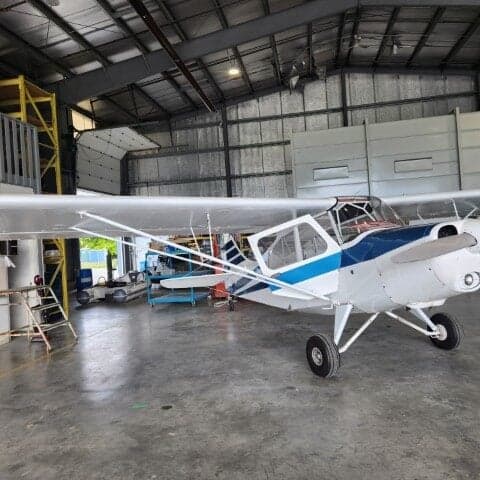 Side view of a white and blue aircraft parked inside a hangar.