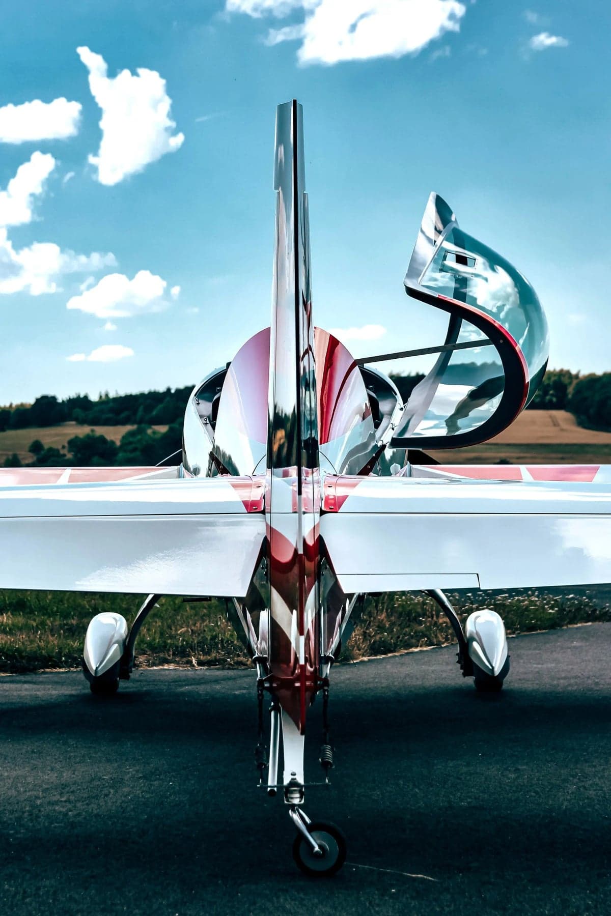 Side view of a red and white Extra EA-300LX parked near a building.