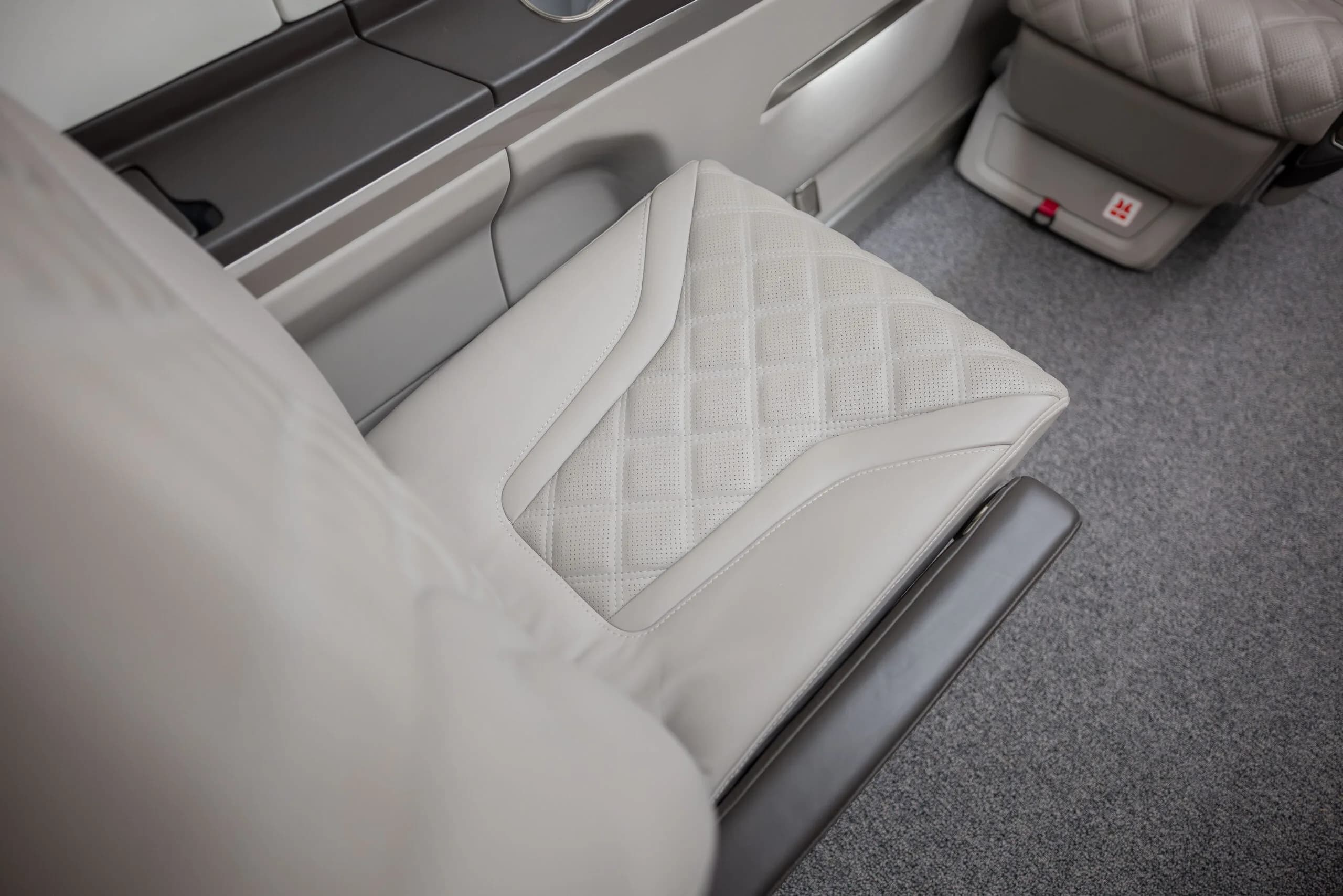 A close-up view of a light gray quilted leather aircraft seat with perforated details.